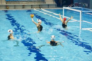 Waterpolo aanvaller heeft bal hoog in de lucht en wil schieten van dichtbij